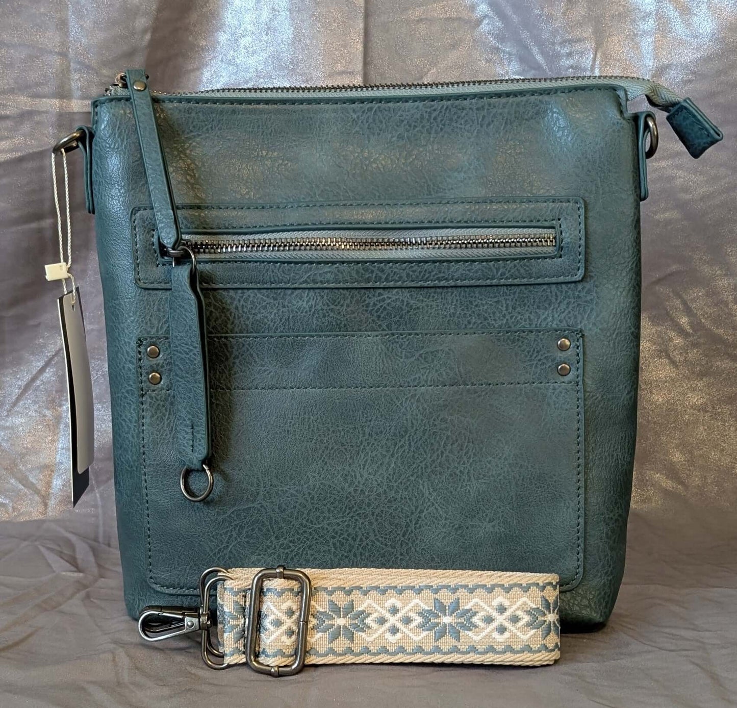Teal crossbody bag with patterned strap showcasing premium faux leather and zip compartments for organization.